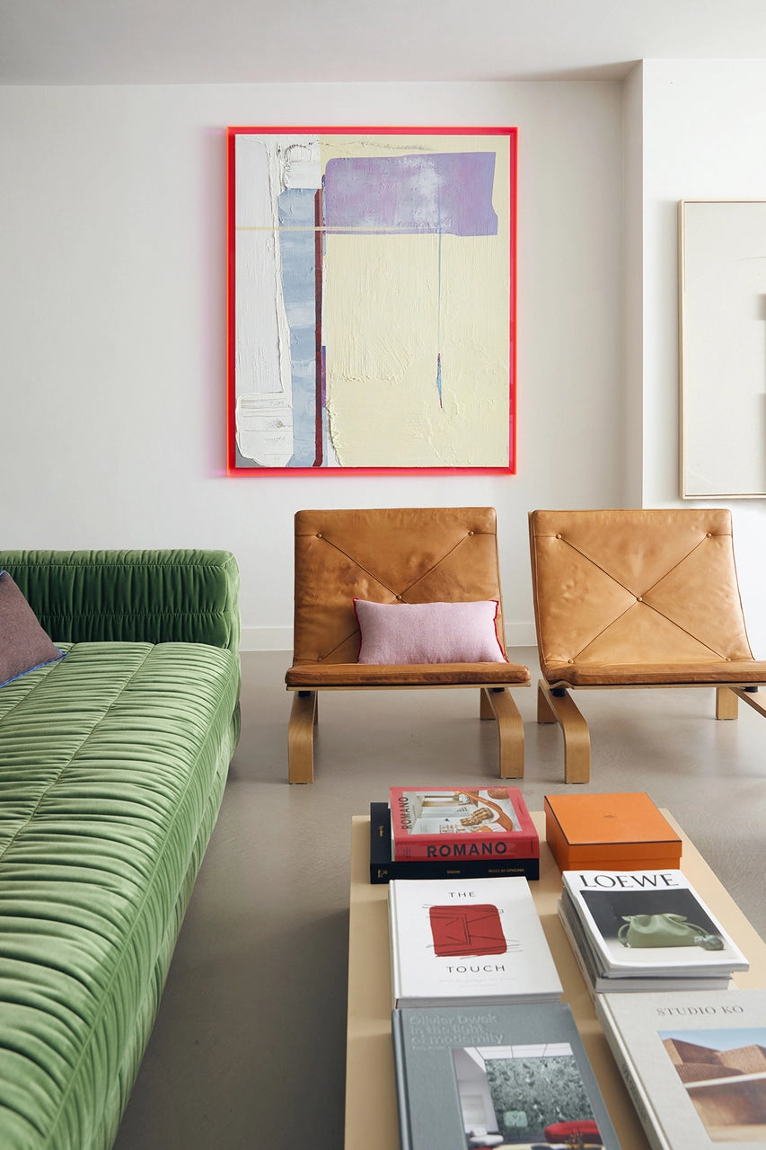 contemporary fresh looking living room with big abstract painting with neon pink frame, two lounge chairs and a pink linen lumbar pillow with red cotton trim