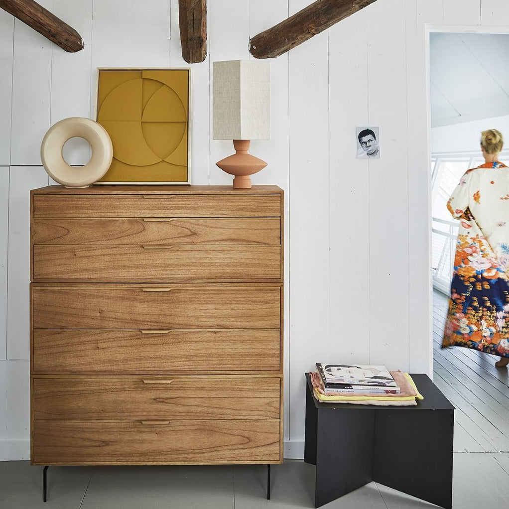 drawer with art work and table lamp in natrula colors and a black metal side table with books and magazines