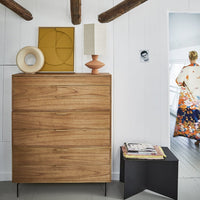drawer with art work and table lamp in natrula colors and a black metal side table with books and magazines