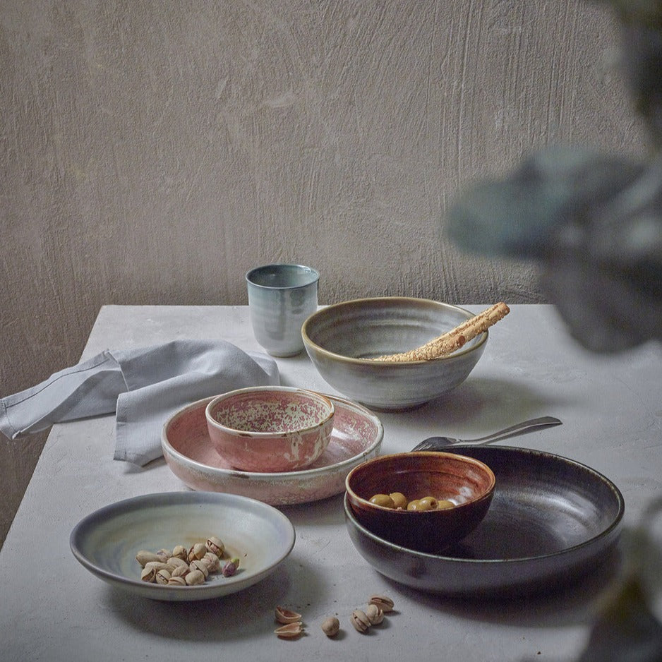 table setting with porcelain bowls and plates in rustic pink, black, brown and grey green colors