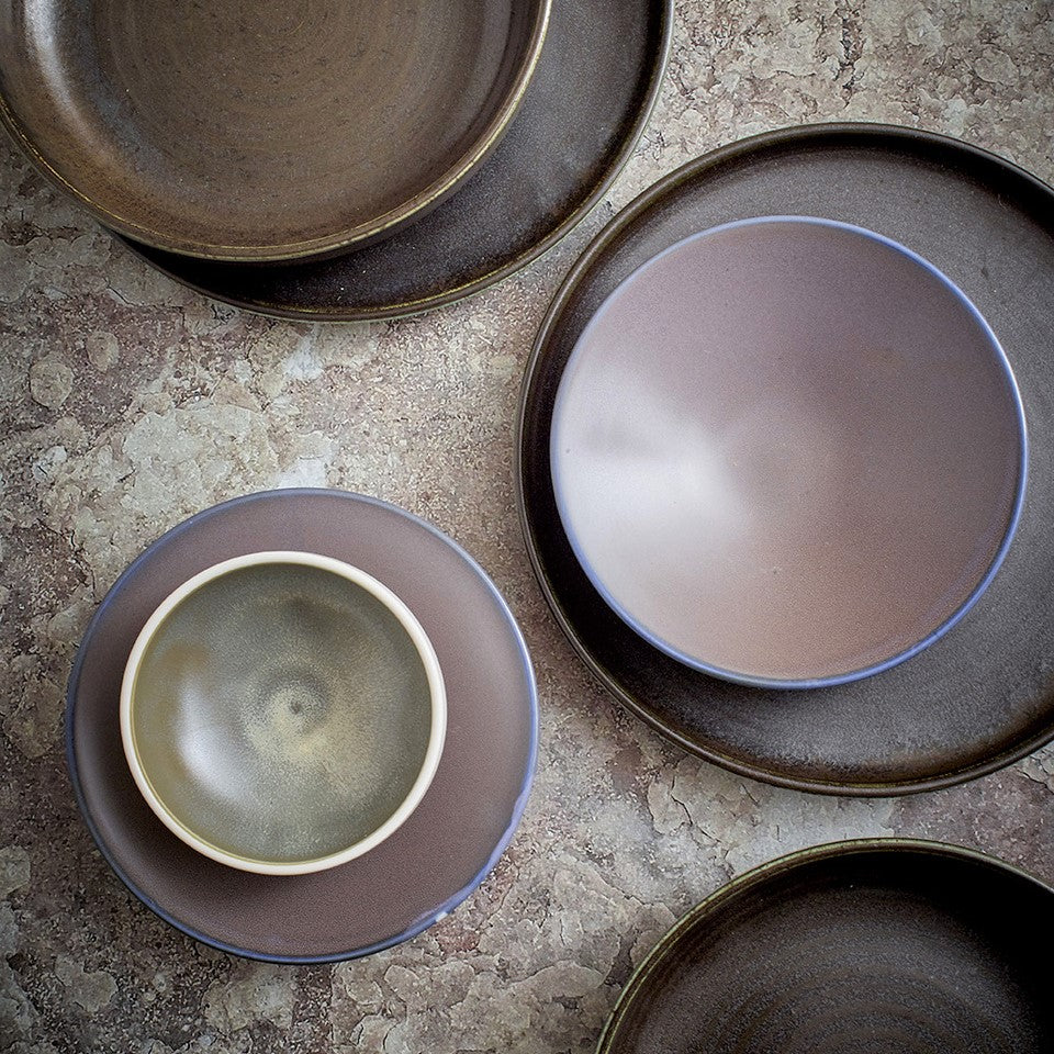 small bowl white outside green inside on a purple side plate in combination with dark brown and black dinner plates