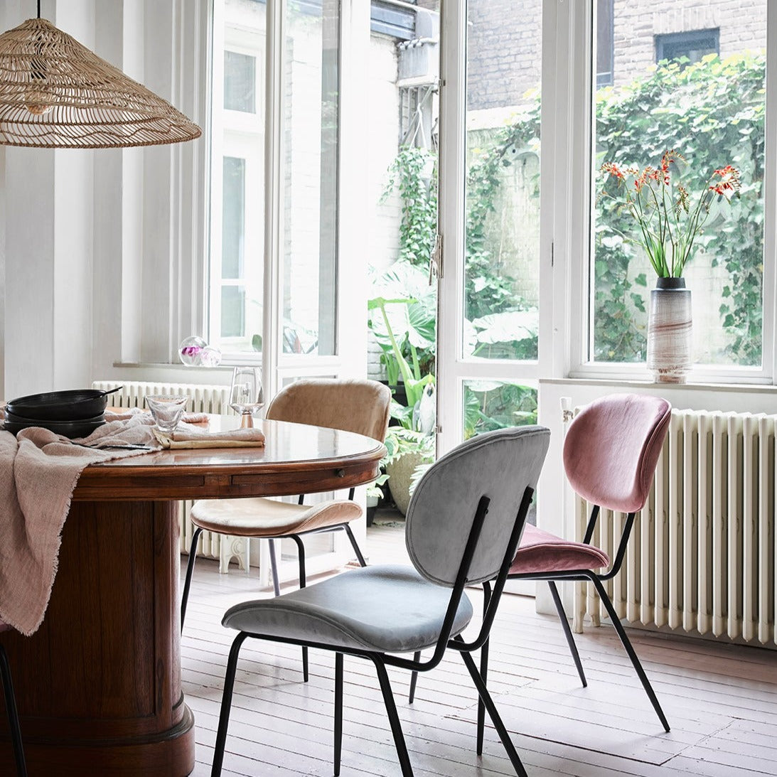 kitchen with pastel colored velvet chairs and a table with salmon colored linen tablecloth draped