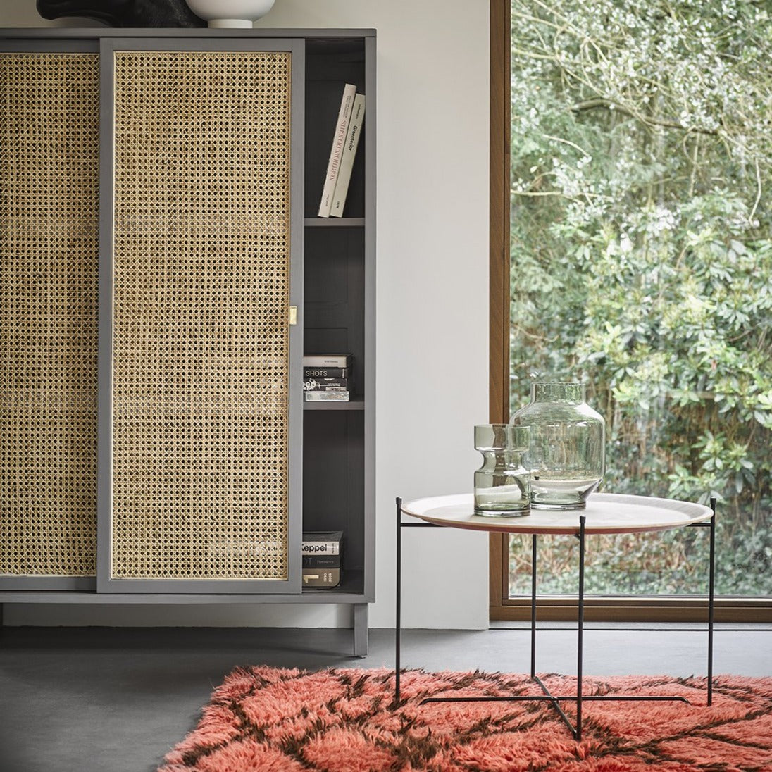 grey webbing door sliding cabinet with walnut tray table and green glass vases