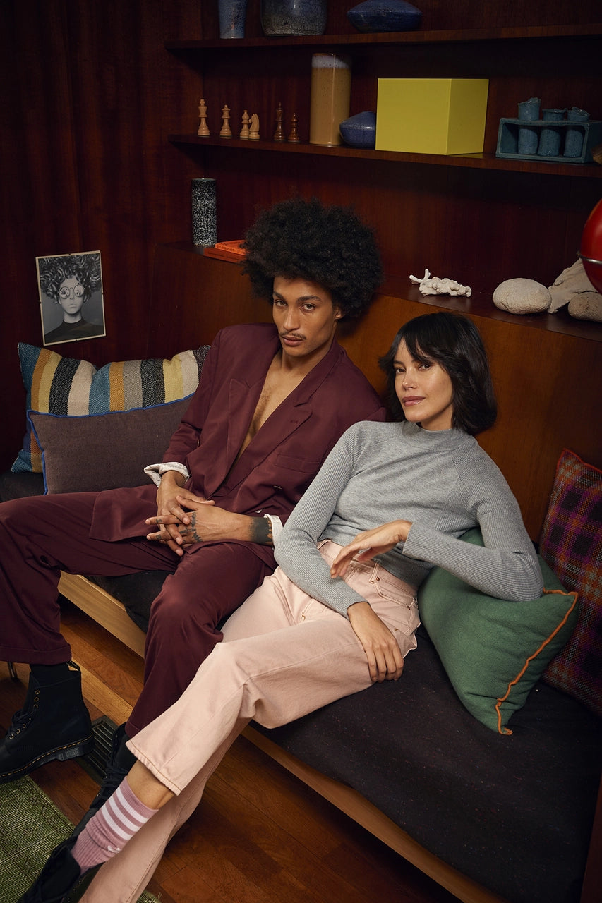 man and woman sitting on a sofa with brown linen pillow with blue trim and green linen pillow with orange trim