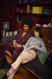 man and woman sitting on a sofa with brown linen pillow with blue trim and green linen pillow with orange trim