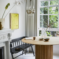 yellow painting, framed with an ash wooden shadow box on a white wall with a black bench and a natural wooden table