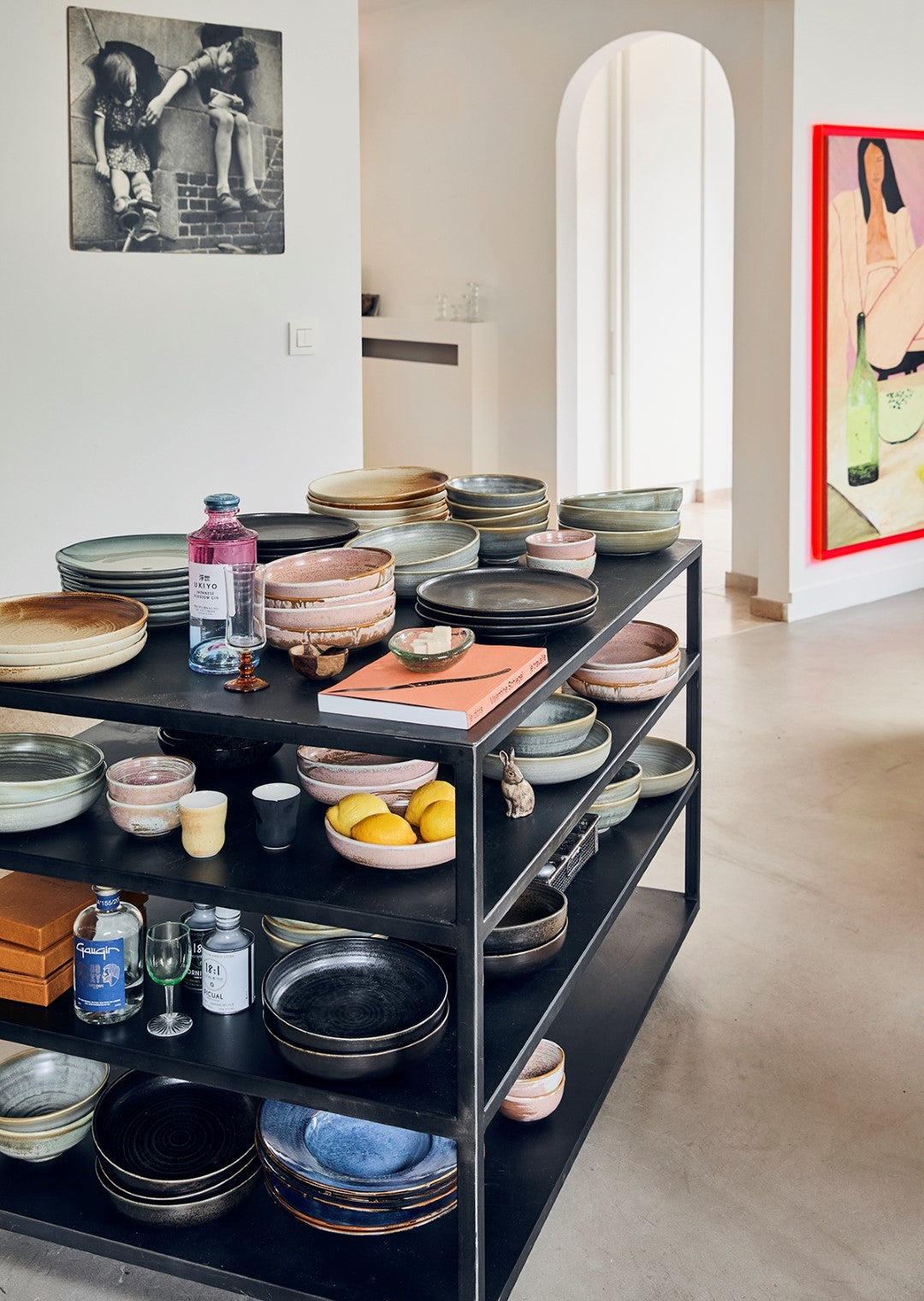 black metal card stcked with pink, blue, green, brown and black plates and pasta bowls